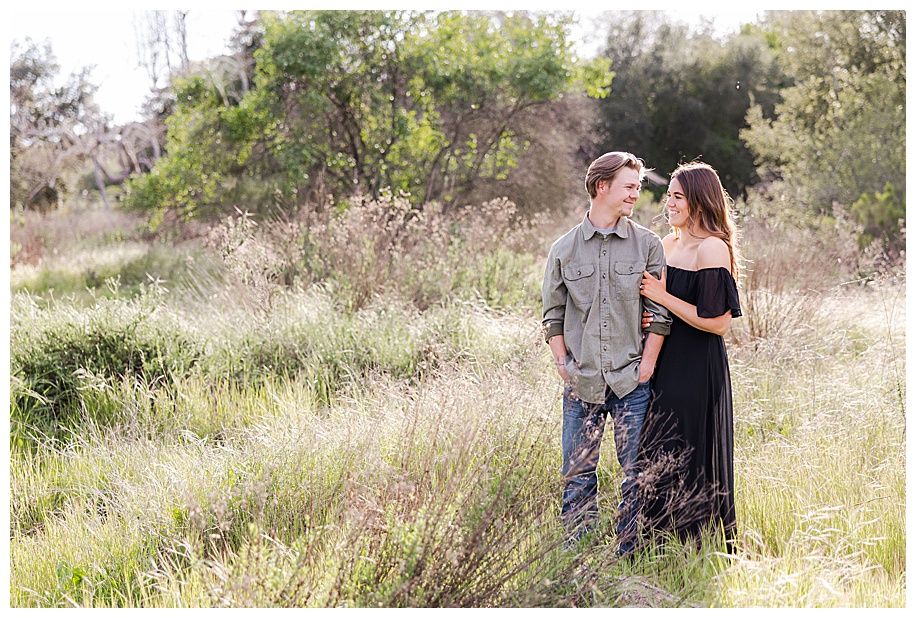 couple standing in grassy field looking at each other