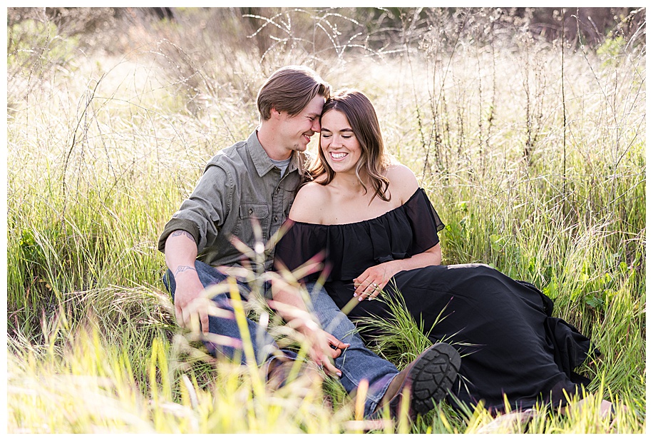 couple snuggling in tall grass while sitting