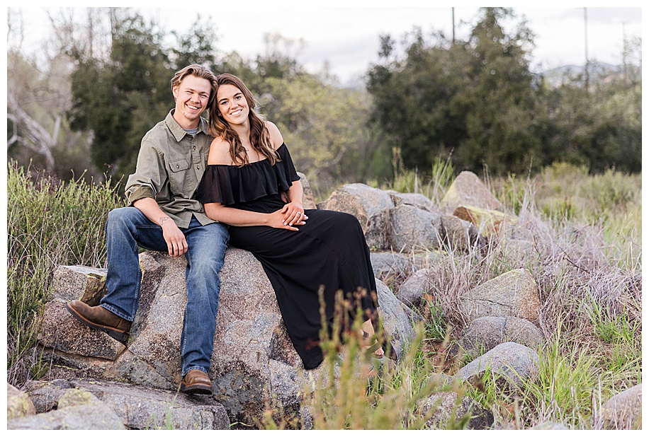 couple sitting on rock and laughing near Sweetwater River Bridge in San Diego