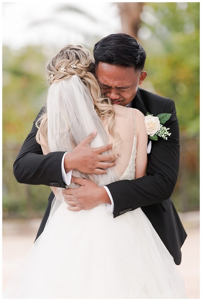 Groom hugging bride and crying during first look