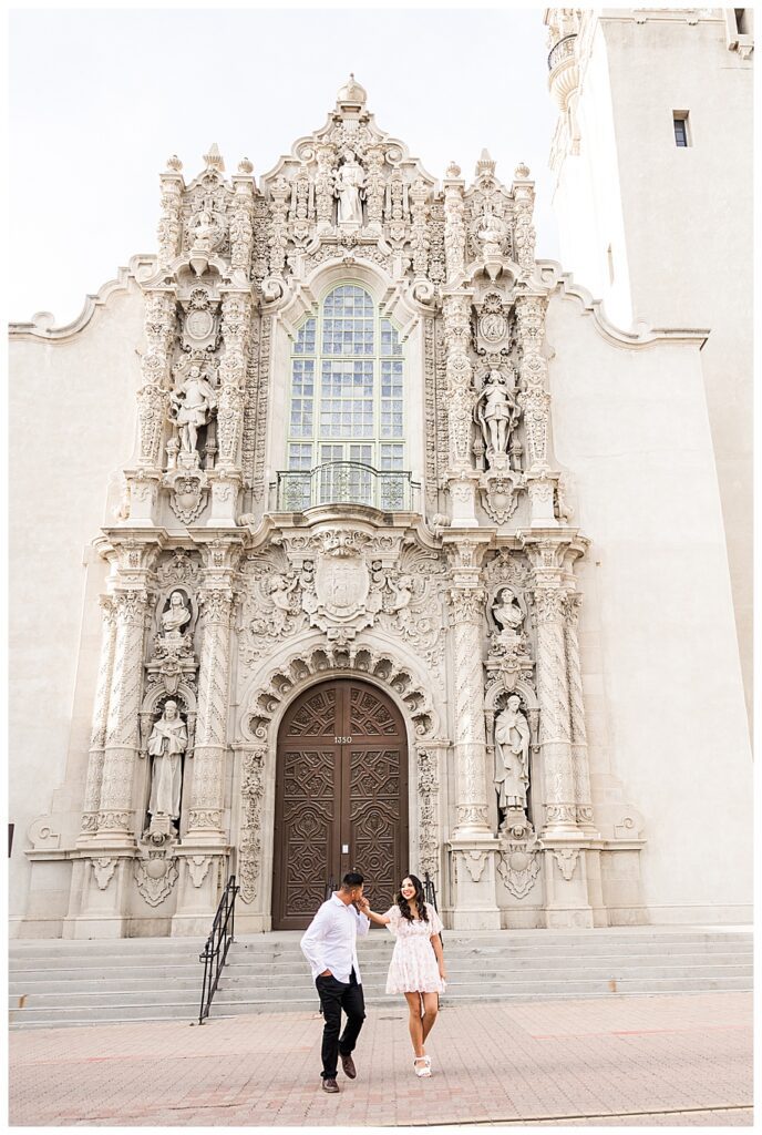 man kissing fiances hand at their San Diego Balboa park engagement session