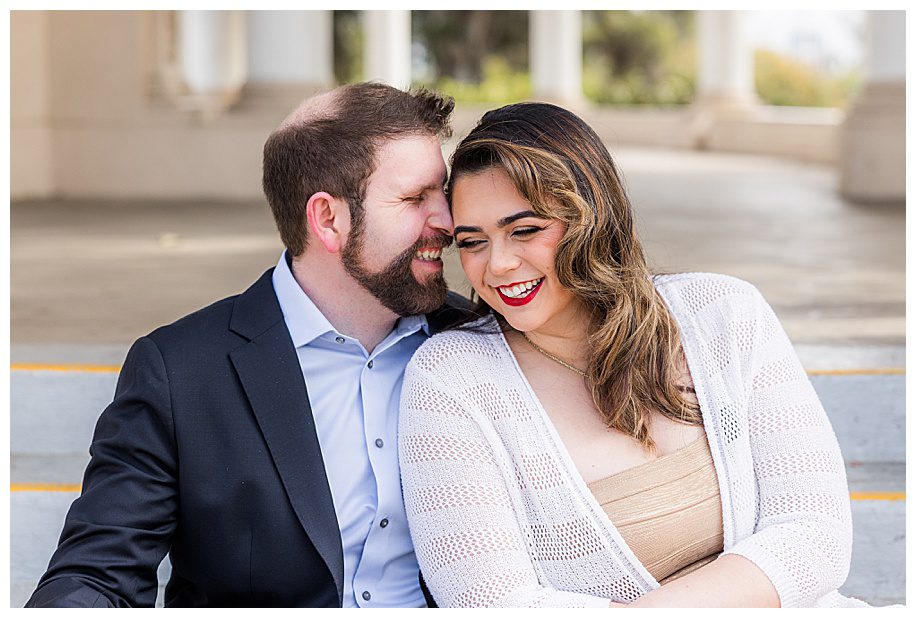 engaged couple sitting on steps laughing
