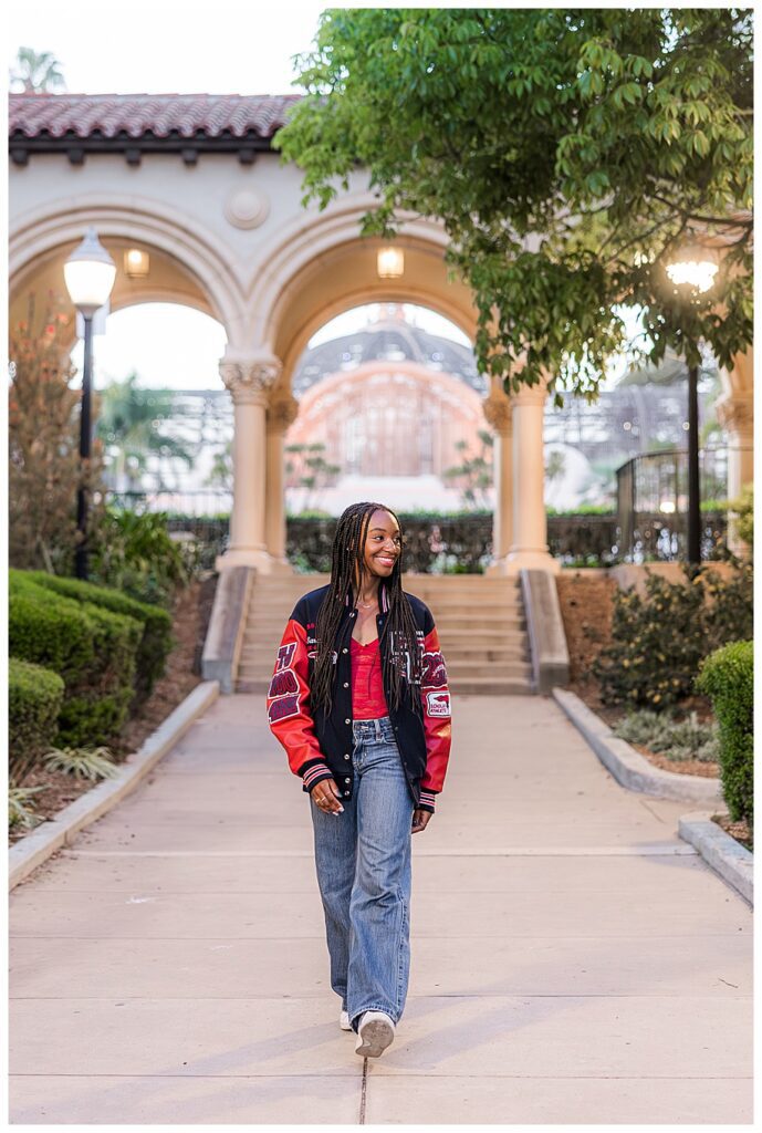 girl walking in lettermans jacket at her Balboa Park Senior photo session