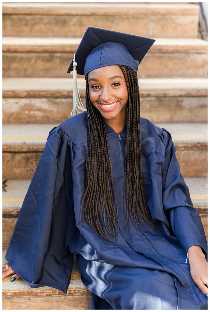 Senior girl in cap and gown sitting on steps
