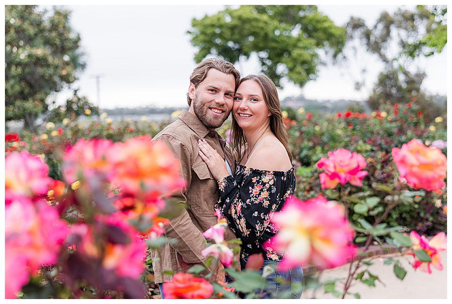 Couple hugging in rose garden at engagement session at Balboa Park