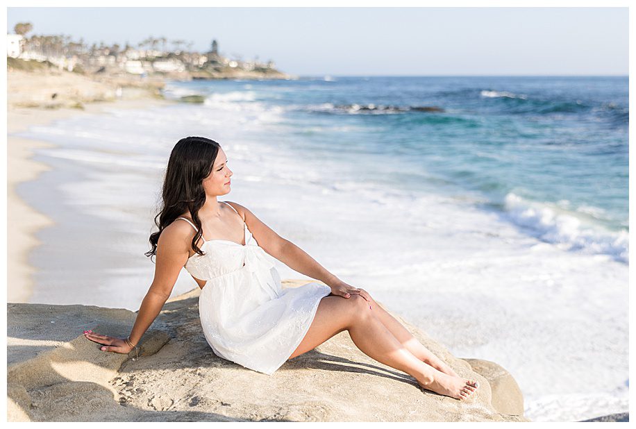 girl sitting on cliff looking at ocean at her  Windnsea senior session