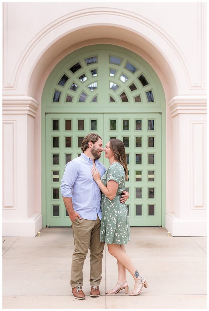 Engaged couple hugging in front of green door