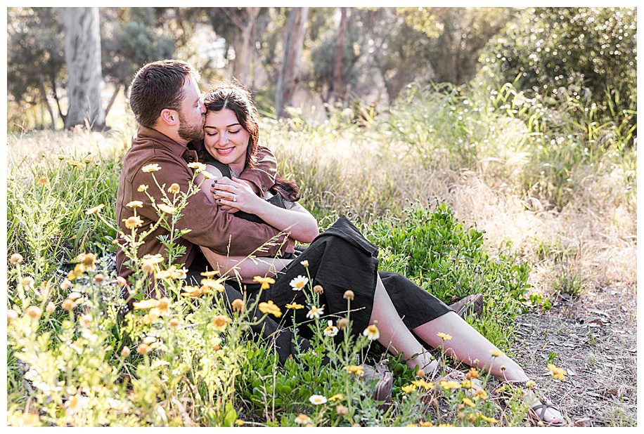 engaged couple sitting in daisies at their Presidio Park Proposal photo session