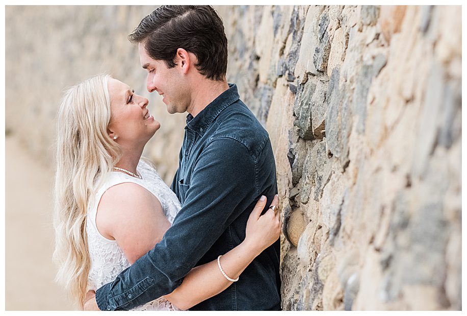 couple leaning against a stone wall at thier La Jolla Cliffs Engagement Session