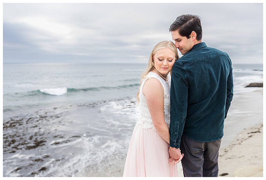 woman with head on fiance's shoulder at their La Jolla Cliffs Engagement Session