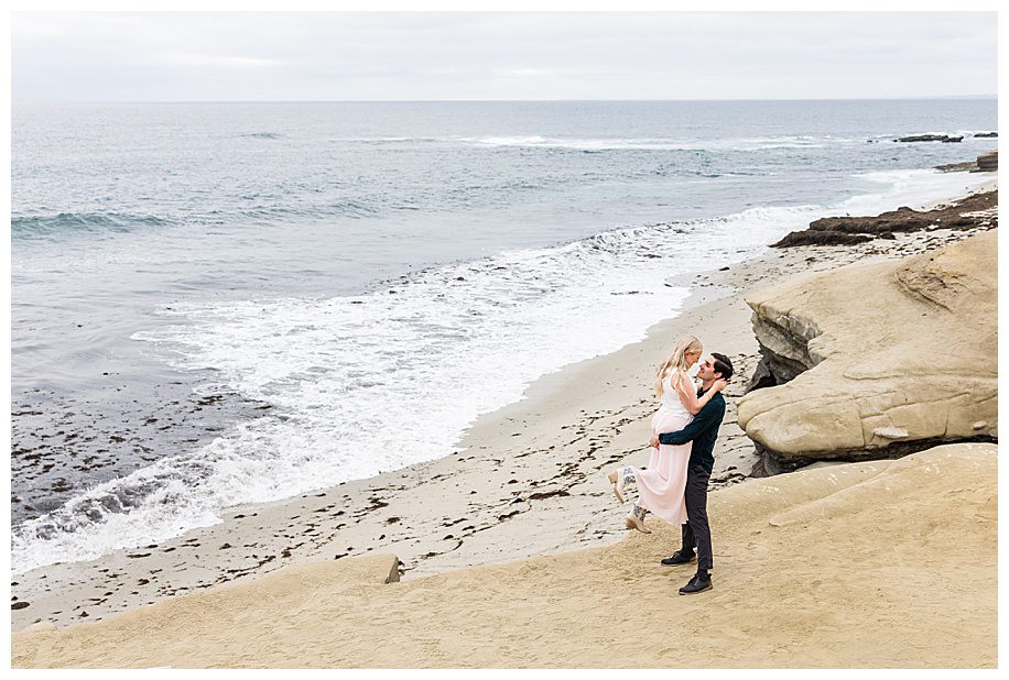 man lifting fiance on the cliffs at her La Jolla Cliffs Engagement Session