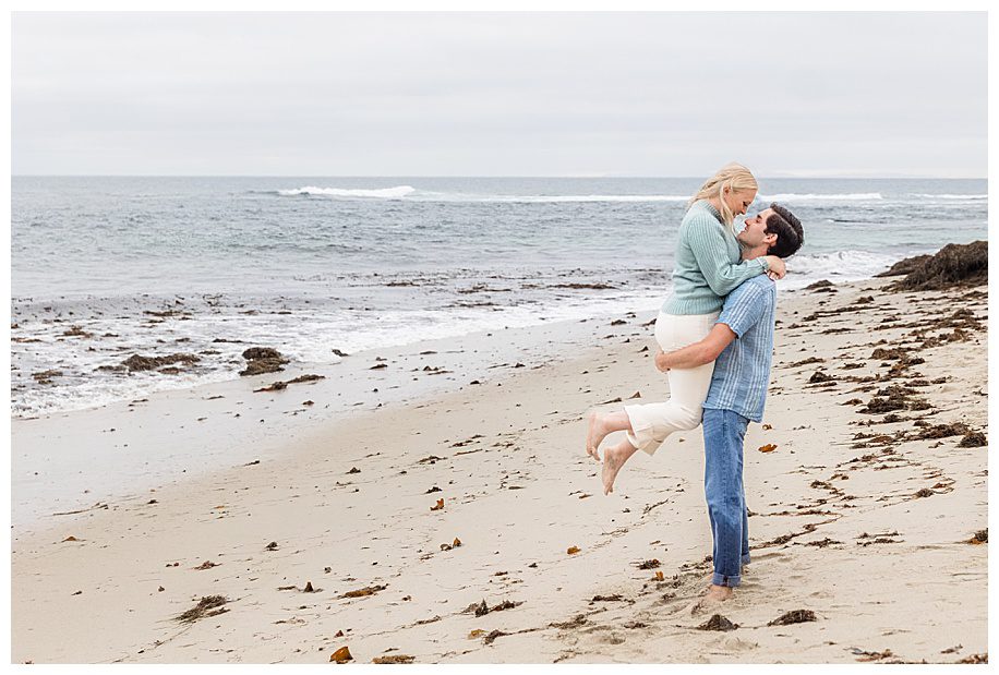 man lifting woman on the beach at their La Jolla Engagement Session