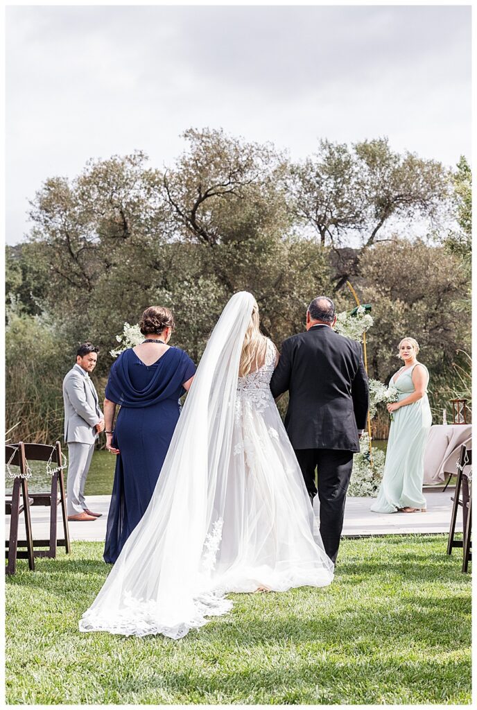 parents and daughter walking toward groom at their WestWynd Ranch Wedding