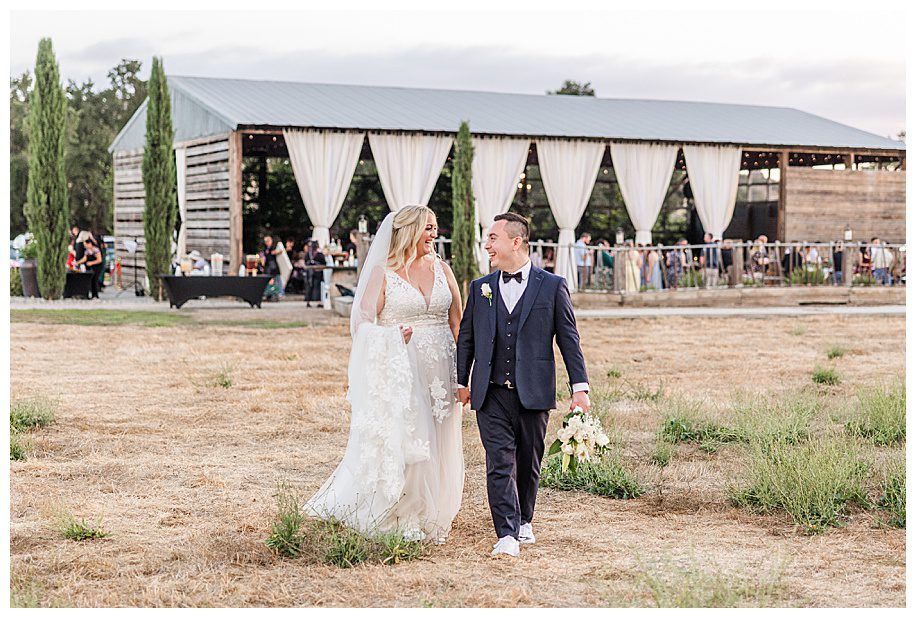 bride and groom outside their barn reception walking in field