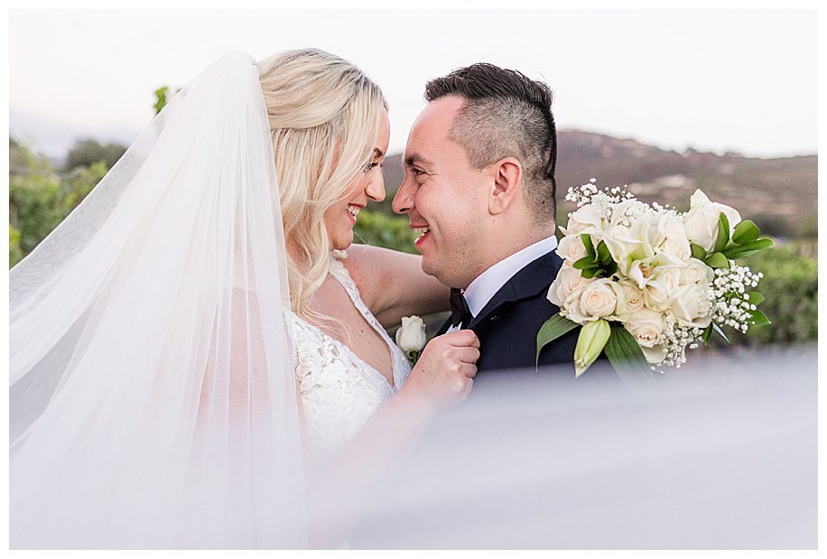 bride and groom hugging with bride's veil flying