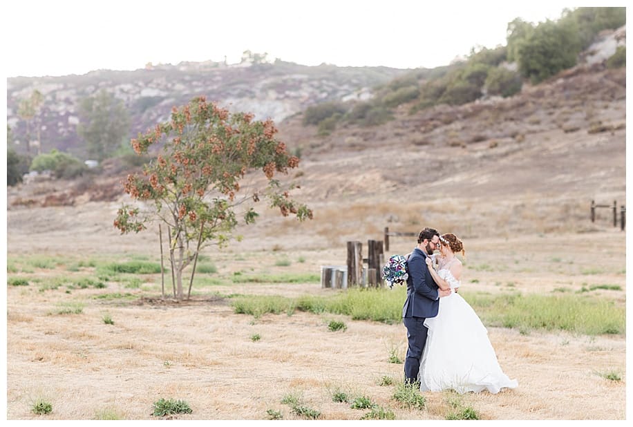 bride and groom hugging in a field at their Westwynd Ranch wedding