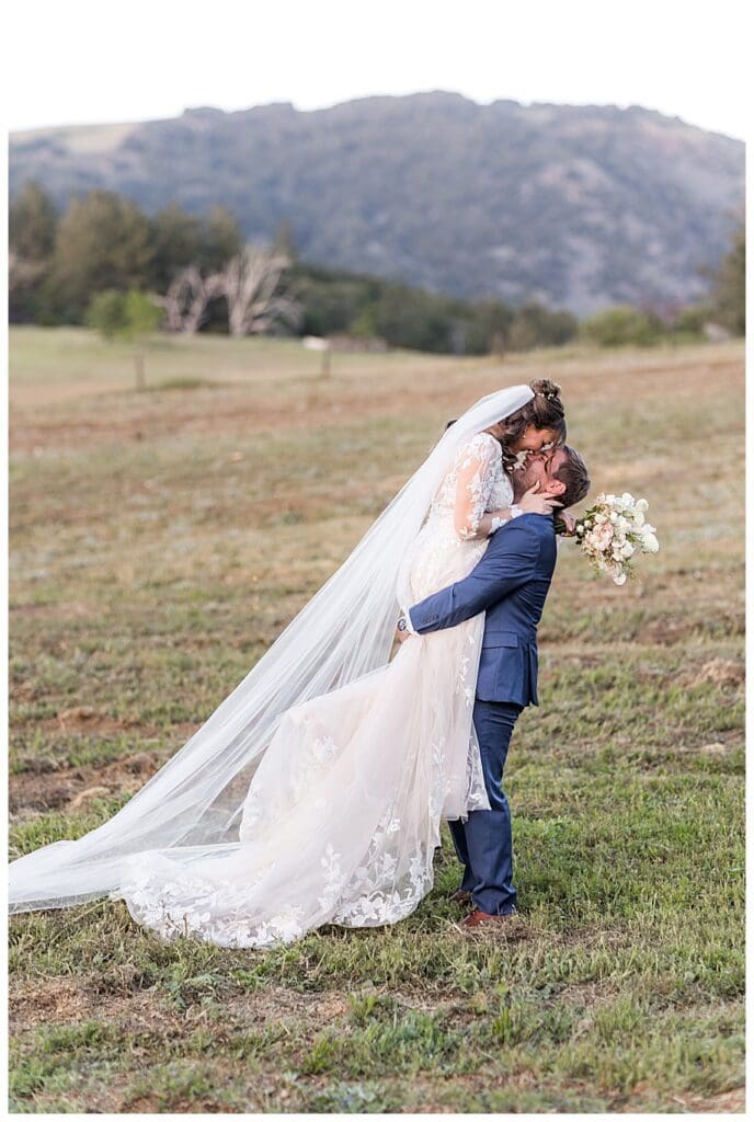 groom lifting bride in field at their Sacred Mountain Wedding