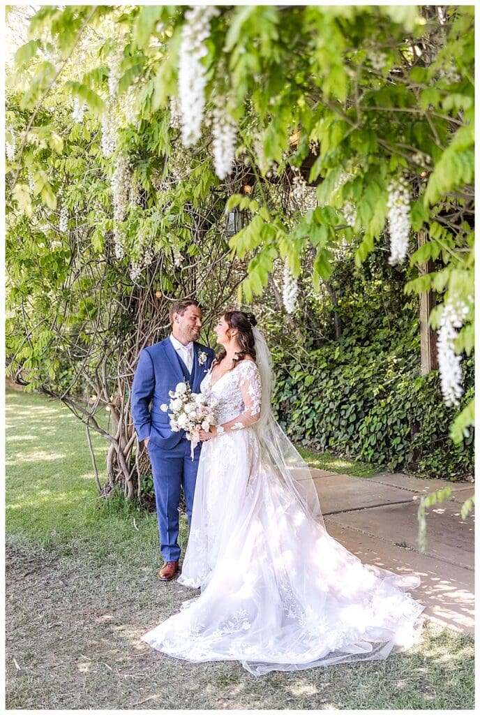 bride and groom hugging under wisteria at their Sacred Mountain Wedding