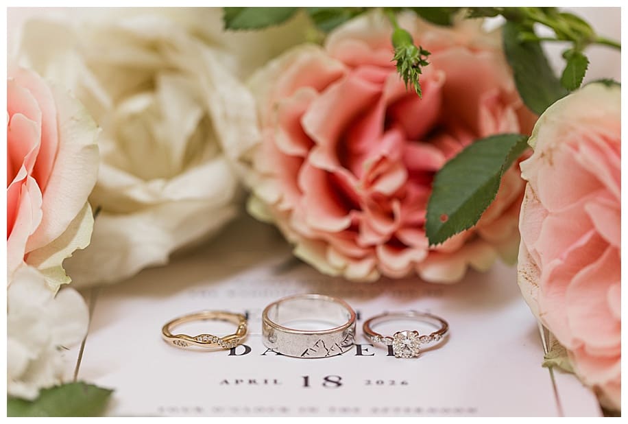 wedding rings on wedding invitation with pink and white flowers