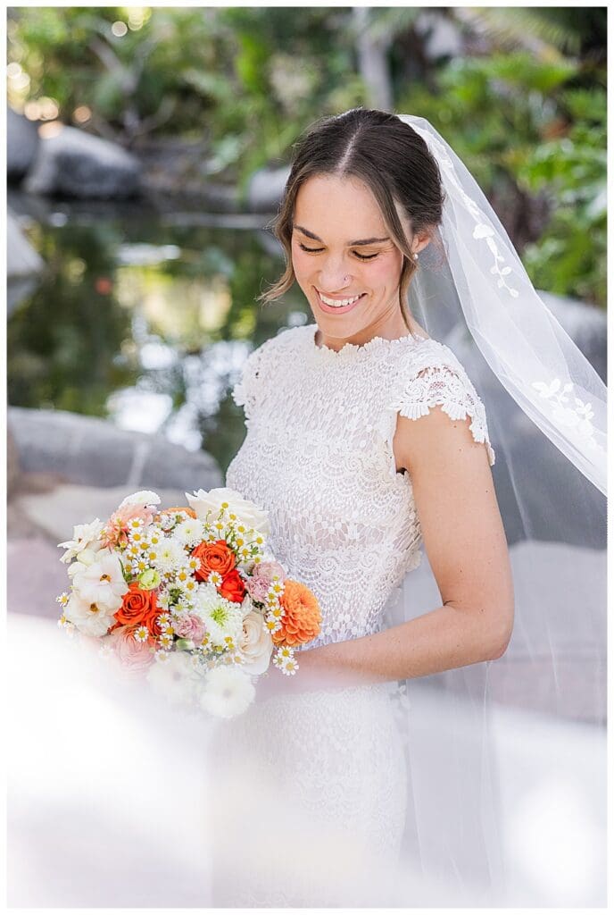 bride looking at bouquet with veil flying