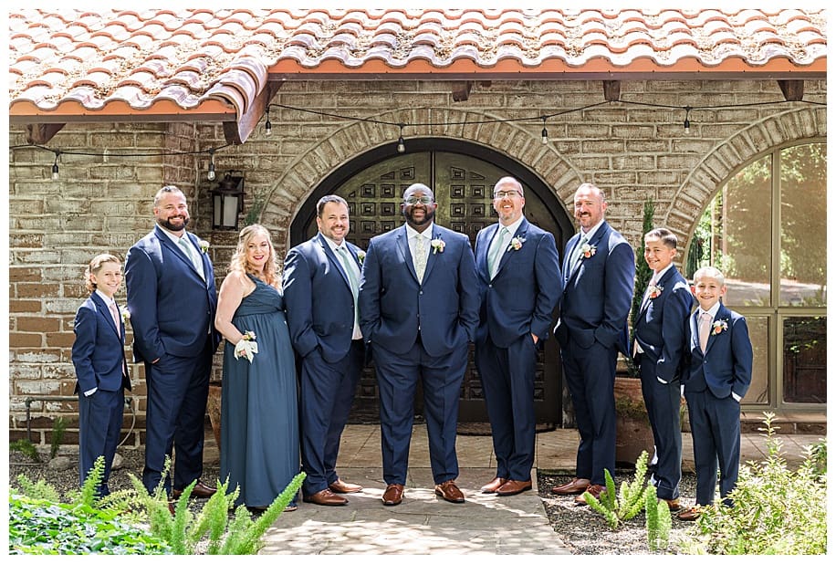 groom and groomsmen standing in front of house at their wedding
