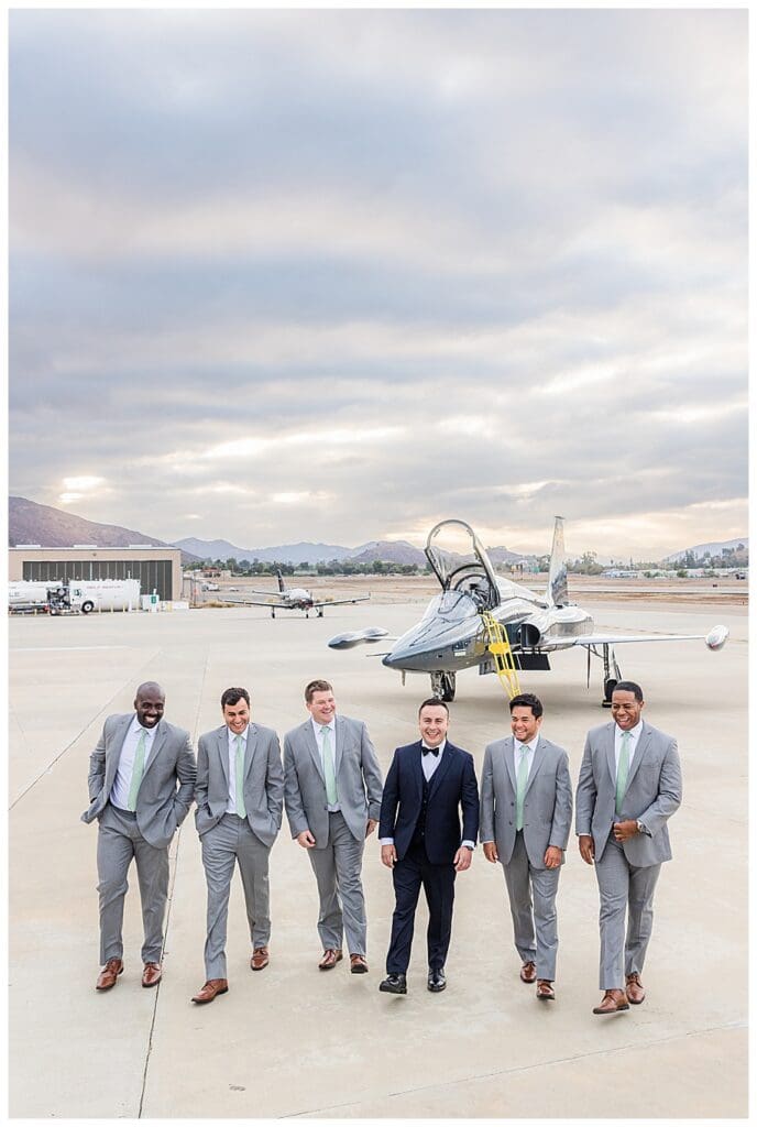 groom and groomsmen standing in front of fighter jet
