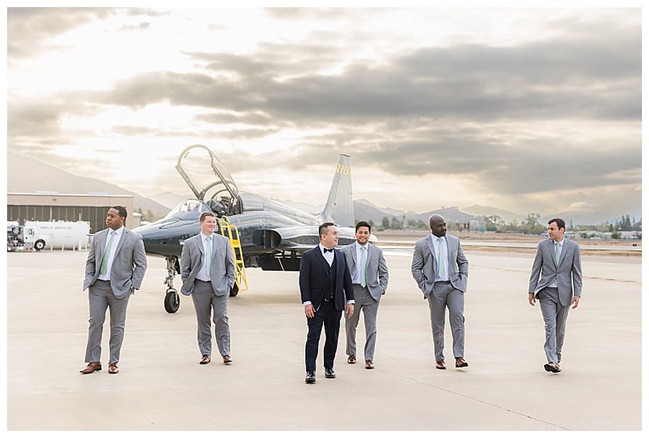 groom and groomsmen walking in front of jet pilot