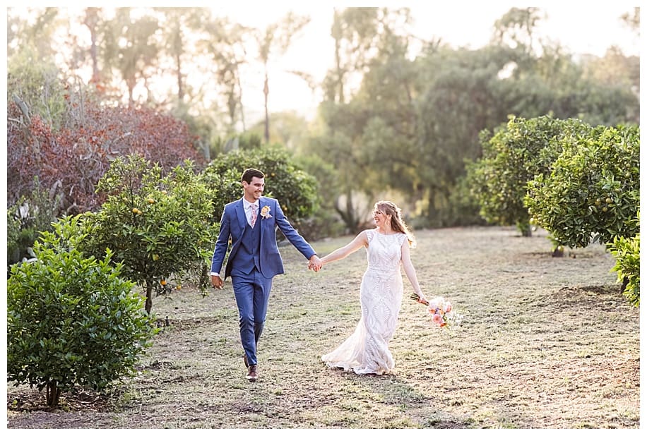 bride and groom running through orchard garden