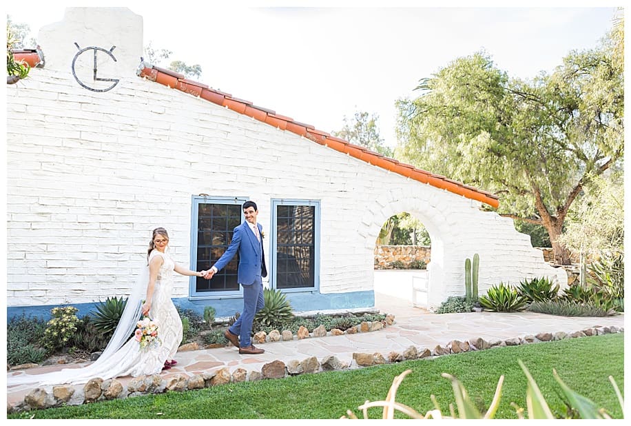 bride and groom walking and holding hands by the adobe at their Leo Carrillo Wedding