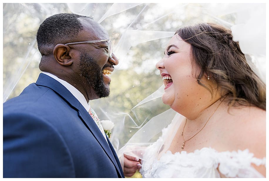 bride and groom laughing under veil